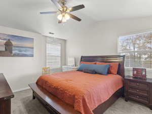 Bedroom featuring light carpet, vaulted ceiling, and a ceiling fan