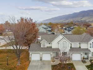 View of front of house with driveway, stone siding, and roof with shingles