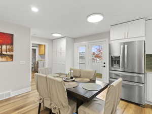Dining room with light wood-style flooring and recessed lighting