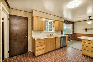 Kitchen with wallpapered walls, light countertops, brick patterned floors, a textured ceiling, and dishwasher