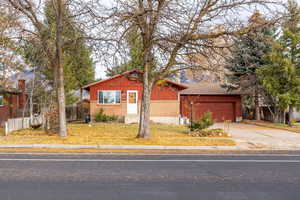View of front of home featuring driveway, brick siding, and a garage