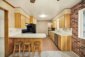 Kitchen with a breakfast bar, light countertops, brick patterned floors, wallpapered walls, and a peninsula