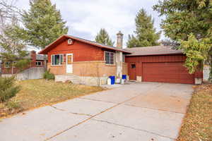 Single story home with brick siding, a chimney, driveway, an attached garage, and roof with shingles