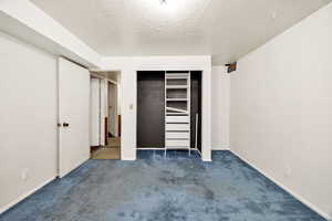 Unfurnished bedroom featuring carpet, a textured ceiling, and a closet