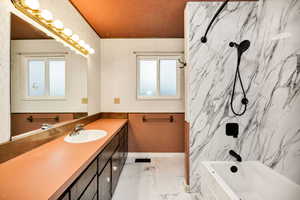Bathroom featuring a combined bath / shower with marble appearance, vanity, and light marble finish flooring