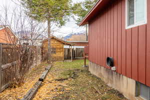 View of property exterior featuring a fenced backyard, board and batten siding, a mountain view, and an outbuilding