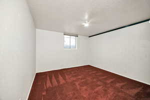 Unfurnished room featuring dark colored carpet and a textured ceiling