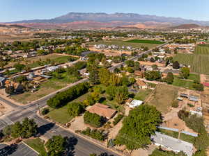 Aerial view of property and surrounding area featuring a mountain backdrop, rural landscape, and large plots for crops