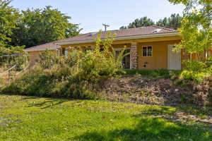 Back of property featuring stucco siding, a tile roof, and a lawn