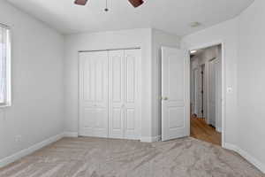 Unfurnished bedroom featuring light colored carpet, a closet, and a ceiling fan