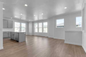 Kitchen featuring gray cabinetry, a center island with sink, a textured ceiling, recessed lighting, and light wood-style flooring