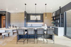 Kitchen with an island with sink, open shelves, a kitchen breakfast bar, pendant lighting, and recessed lighting