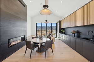 Dining space with a fireplace, a mountain view, recessed lighting, light wood-type flooring, and high vaulted ceiling