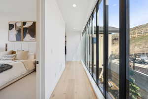 Hallway featuring expansive windows, light wood-type flooring, and recessed lighting
