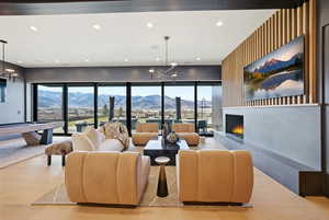 Living area with a chandelier, a warm lit fireplace, recessed lighting, wood finished floors, and an accent wall