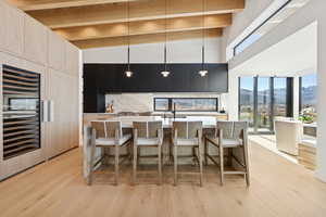 Kitchen with a mountain view, a breakfast bar, hanging light fixtures, light brown cabinetry, and modern cabinets