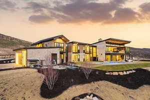 Rear view of house featuring a balcony, a patio, a mountain view, a chimney, and stone siding