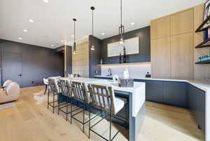 Kitchen featuring modern cabinets, open shelves, light brown cabinets, a kitchen island, and light wood-style flooring
