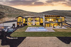 Rear view of house with a lawn, a patio, a balcony, and a mountain view