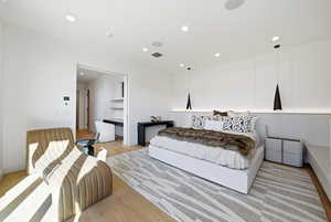 Bedroom with light wood-style flooring, recessed lighting, and an office area