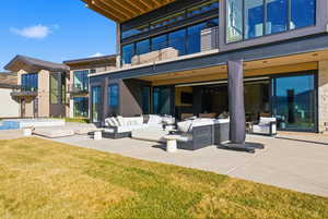 Back of house featuring an outdoor living space, a balcony, a patio, and a yard