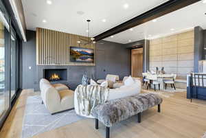 Living area with an accent wall, light wood-style floors, recessed lighting, and a lit fireplace