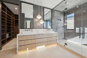 Bathroom with a shower stall, double vanity, healthy amount of natural light, light flooring, and recessed lighting