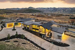 View of front of home with driveway, a metal roof, a mountain view, a patio, and stone siding