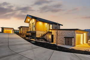 Modern home with stone siding, an outbuilding, stairs, and driveway