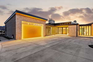 Property exterior at dusk with stone siding, driveway, and a chimney