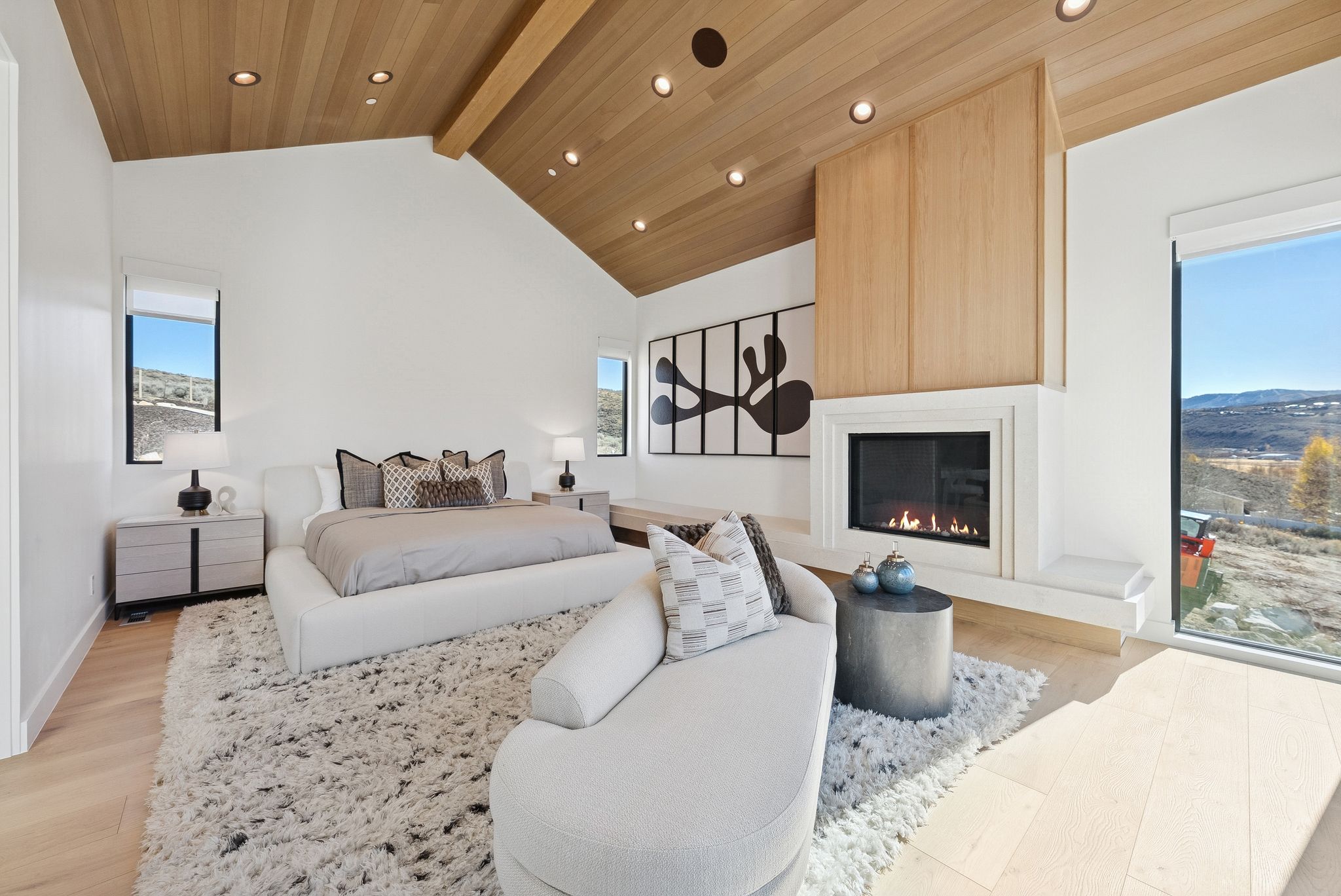 Bedroom featuring multiple windows, light wood-style flooring, a fireplace, a wooden ceiling with exposed beams, and high vaulted ceiling