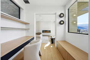Home office featuring a glass covered fireplace, light wood finished floors, and a mountain view