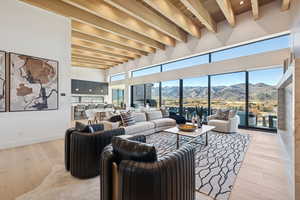 Living room with a mountain view, light wood-type flooring, and a wood ceiling with exposed beams