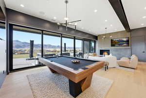 Rec room with billiards table, a mountain view, light wood-style flooring, recessed lighting, and a chandelier