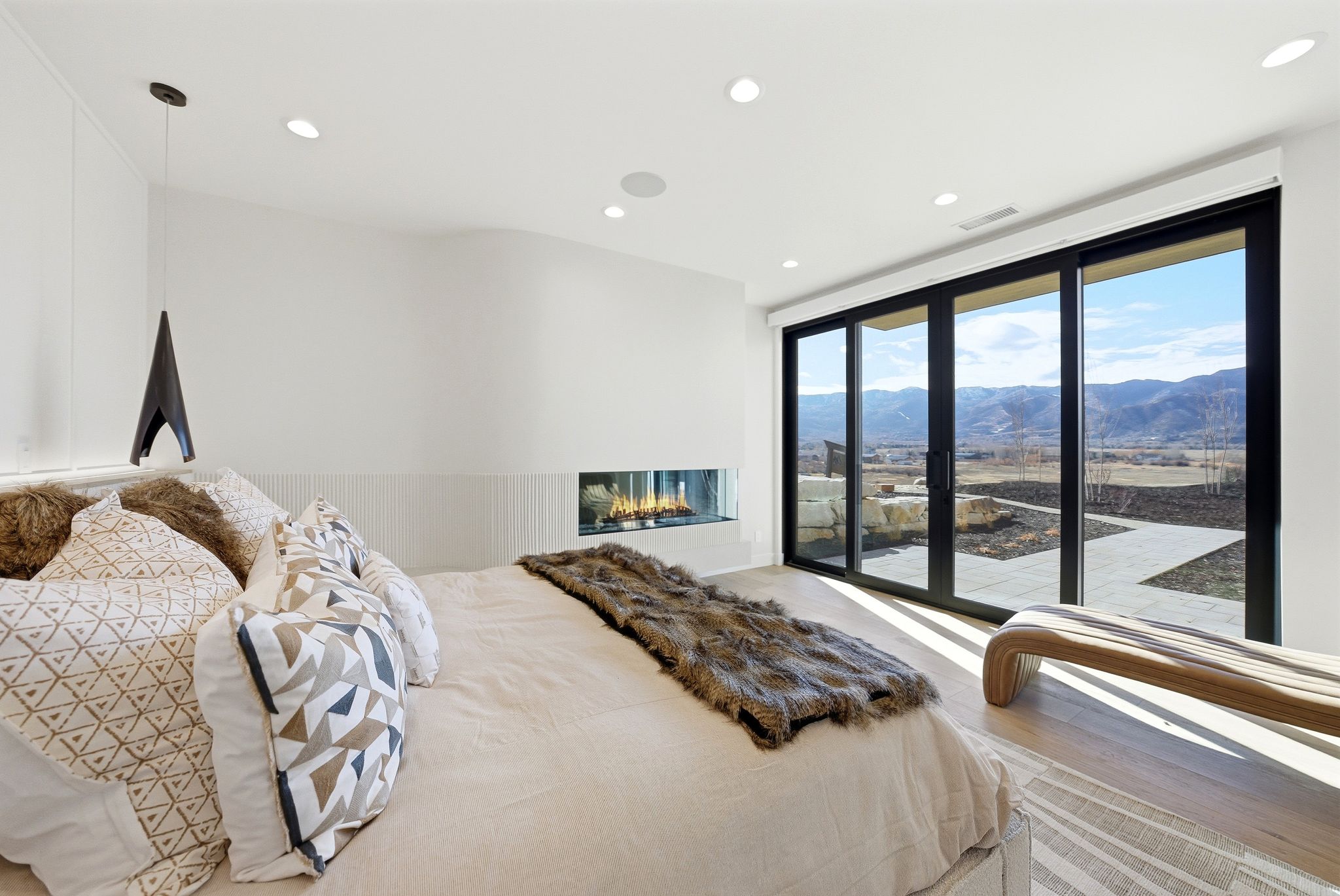 Bedroom with a mountain view, access to exterior, wood finished floors, recessed lighting, and a glass covered fireplace