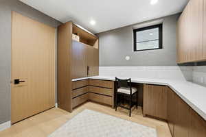 Office with built in desk, light wood finished floors, and recessed lighting