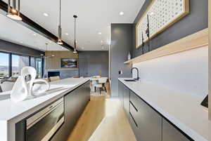 Kitchen with open shelves, modern cabinets, stainless steel microwave, recessed lighting, and light stone countertops