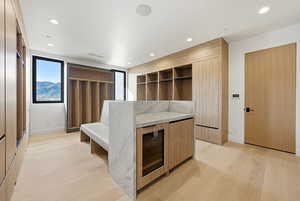Bedroom with wine cooler, light wood finished floors, recessed lighting, and a closet