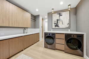 Laundry area with light wood-type flooring, recessed lighting, independent washer and dryer, and cabinet space