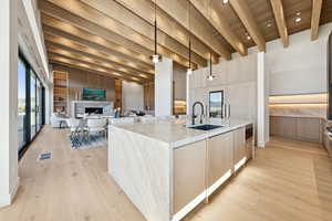 Kitchen with light brown cabinetry, modern cabinets, light stone countertops, a wooden ceiling with exposed beams, and recessed lighting