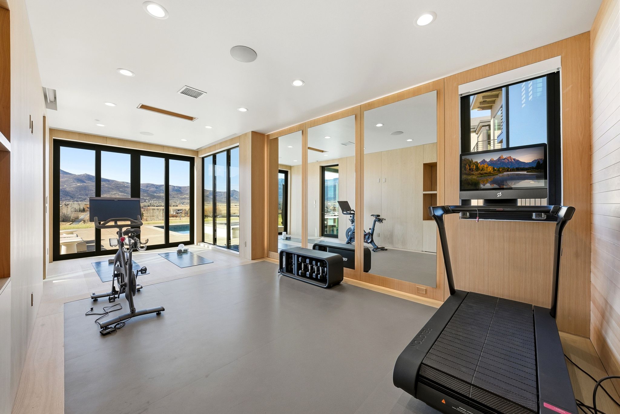 Exercise room with a mountain view, plenty of natural light, a wall of windows, and recessed lighting