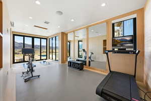 Exercise room with a mountain view, plenty of natural light, a wall of windows, and recessed lighting