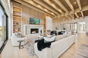 Living area with built in features, a high end fireplace, light wood finished floors, a wood ceiling with exposed beams, and recessed lighting