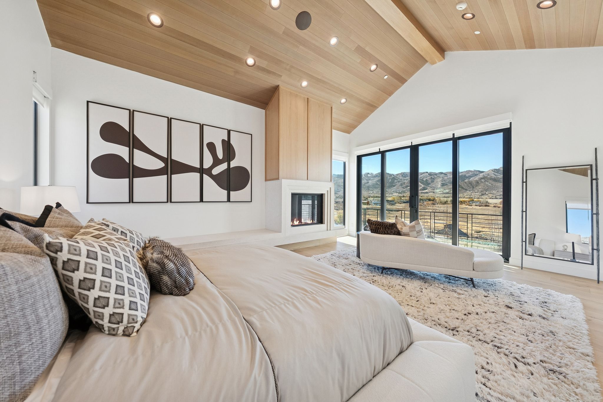Bedroom with high vaulted ceiling, a fireplace, light wood finished floors, a mountain view, and a wood ceiling with exposed beams