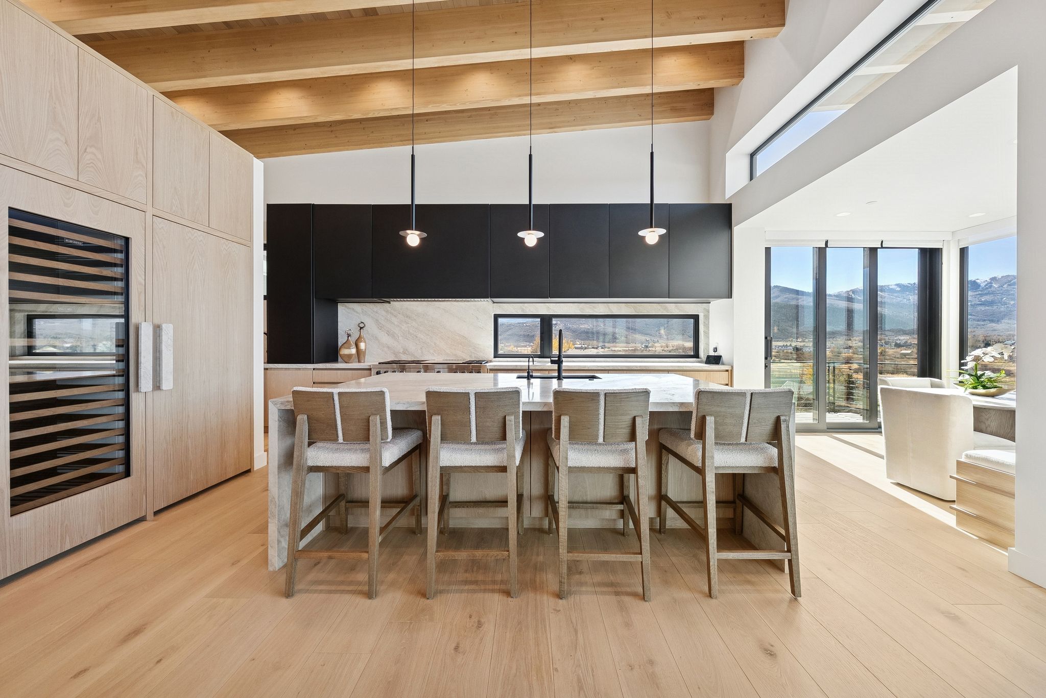 Kitchen with a mountain view, a breakfast bar area, decorative light fixtures, modern cabinets, and a kitchen island with sink