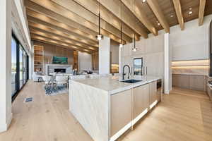 Kitchen with light brown cabinets, modern cabinets, light stone counters, and wooden ceiling