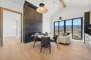 Dining area with beamed ceiling, light wood-style flooring, a mountain view, a large fireplace, and recessed lighting