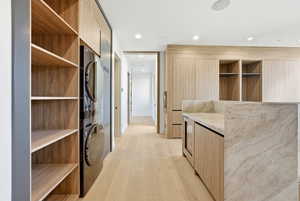 Spacious closet featuring light wood-style floors and stacked washer and clothes dryer