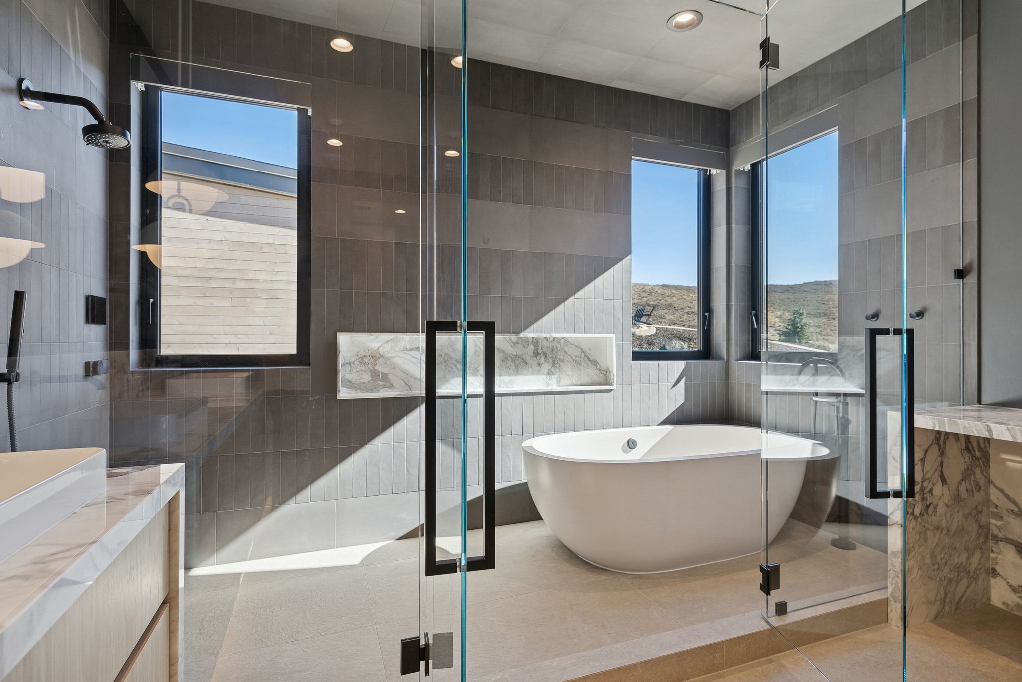 Bathroom featuring vanity, a soaking tub, a tile shower, healthy amount of natural light, and tile walls
