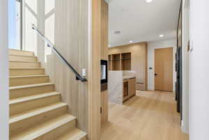 Stairs with wood finished floors, recessed lighting, and beverage cooler